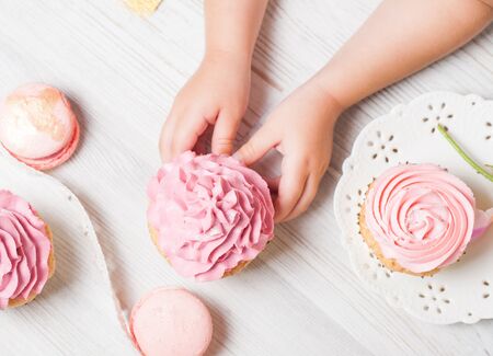 Cute little girl holding birthday cupcakes in kitchen. Festive and holiday conceptの写真素材
