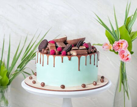 Chocolate cake with sweet raspberries and candies with Mint glaze on white wooden stand. close up