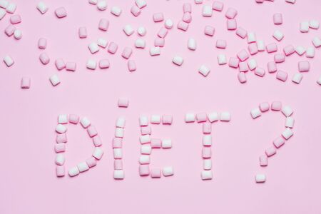 Pink and white Marshmallows on pink background with word diet. Top view, flat lay. Concept of not healhy eating and diets.の写真素材