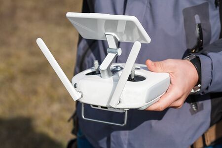 Man holds a drone remote controller in his hands. Close-up of quadrocopter RC during flight. Pilot...