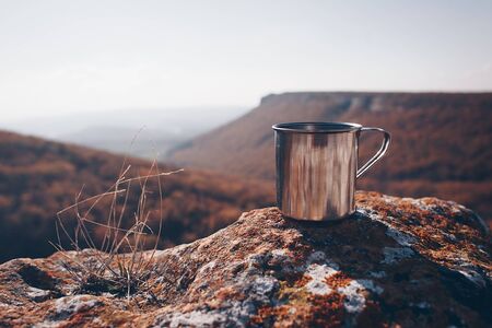 Metal cup on rock in mountain forest. Autumn colors, close up, copyspace. beautiful landscapeの写真素材