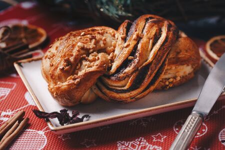 Tasty homemade bun with nuts and cinnamon on holiday christmas table, close up.
