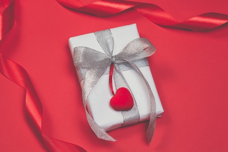 Gift box with hearts on red background. Top view, flat lay. St. Valentines day greetind conceptの写真素材