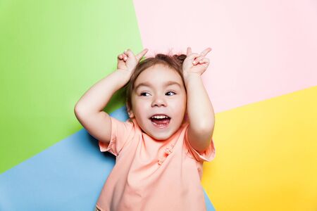 Pretty 4-year little girl with funny face on multicolor background. Bright colors and stylish pictureの写真素材