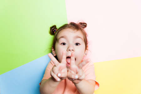 Pretty 4-year little girl with funny face on multicolor background. Bright colors and stylish pictureの写真素材