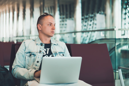 man sitting at the airport working in his laptopの写真素材