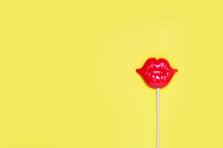 Red lips for fun on yellow festive background. Bright celebration concept. Top view, flat lay. Copy space for text.の写真素材