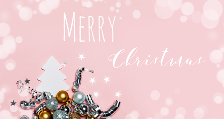 Christmas background with golden decorations put as frame on pink background. Bright and festive flat lay. Top view. Greetings for christmas or new year.の写真素材