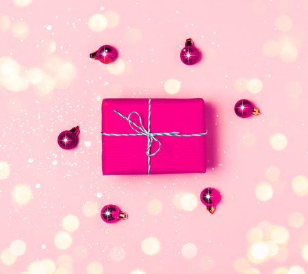 Christmas background with purple decorations and gift present box put as frame on pink background. Magic bokeh lights. Bright and festive flat lay. Top view, Greetings for christmas or new year.の写真素材