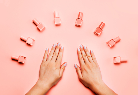 Beautiful female hands with trendy stylish manicure on trendy Living Coral background. Color of the year 2019 beauty concept. Top view, flat lay.の写真素材