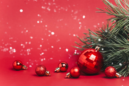 Christmas red background with christmas balls and snow falling on them. Christmas festive concept.の写真素材