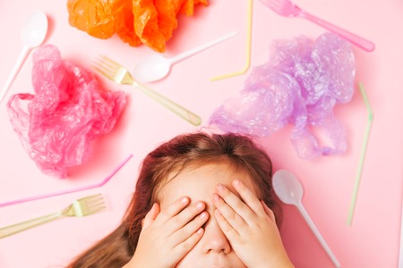 Little girl closing her eyes in surround of plastic trash, plastic bags and garbage. Environment pollution concept.の写真素材
