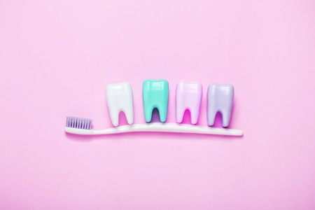 Toothbrush and big tooth on pink background. Teeth care minimalism concept. Copyspace for your text.の写真素材