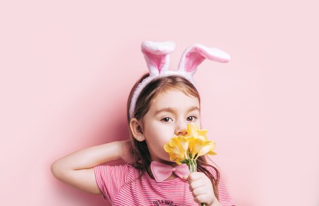 Cute little girl with bunny ears on pink background.