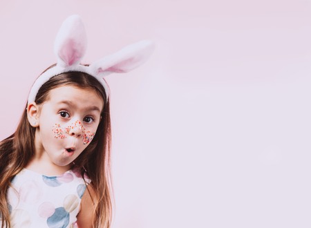 Cute little girl with bunny ears on pink background.