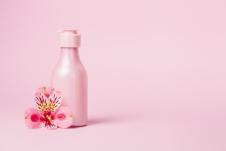 Creative minimal beauty and health background with pink bottle. Minimal top view and flat lay of cosmetic on pink and blue trendy background.の写真素材