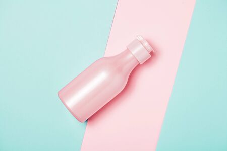 Creative minimal beauty and health background with pink bottle. Minimal top view and flat lay of cosmetic on pink and blue trendy background.の写真素材