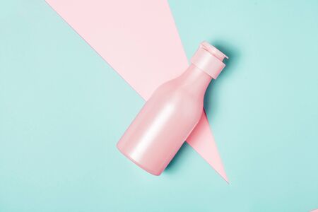 Creative minimal beauty and health background with pink bottle. Minimal top view and flat lay of cosmetic on pink and blue trendy background.の写真素材