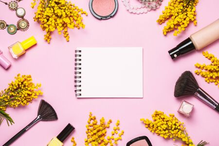 Yellow spring flowers, notebok and some cosmetics on pink trendy background, top view, flat lay. Copy space for textの写真素材