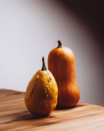 Two pumpkins on wooden table with art light. Halloween or thanksgiving day concept.の写真素材