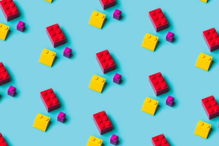 Top view of plastic blocks background. Flat lay image of toy background made with pink building blocks from child constructor. Bright pink plastic building blocks on yellow background.の写真素材