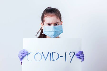Little girl holding in hands poster with COVID-19 word.の写真素材
