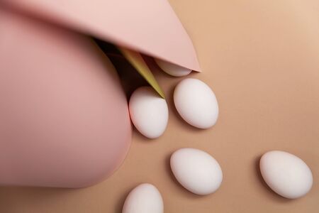 Creative Easter beige and pink background with white eggs. Easter holiday minimal concept.