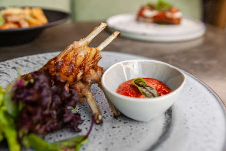fried lamb ribs with tomato sauce and fresh greensの写真素材