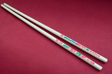two chopsticks with hieroglyphics on the red backgroundの写真素材