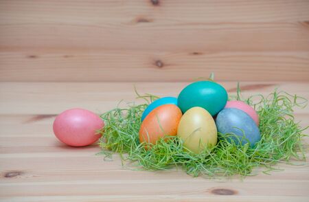 happy easter eggs pastel colored in a nest on the vintage wooden background