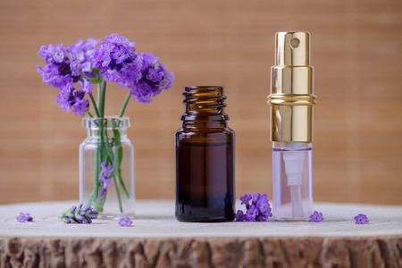 lavender water and essential oil bottle and fresh lavender flowers for relax on brown background