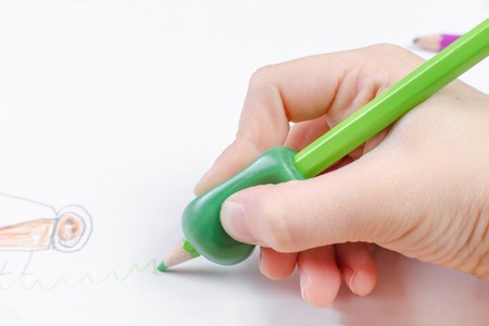 childs hand with writing tool for help by incorrect holding of pencilの写真素材
