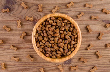 dog food in a bowl and snack like bones on wooden background, flat layの写真素材