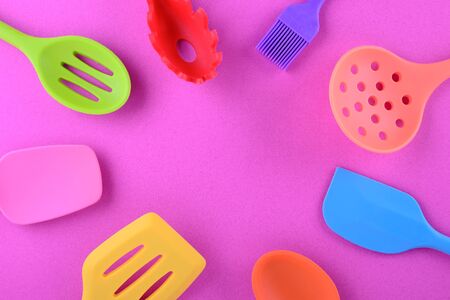 bright multi colored kitchen utensils on purple background with copy spaceの写真素材