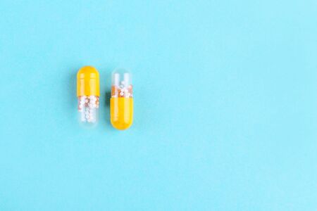 two medicine capsules on blue background with copy space flat layの写真素材