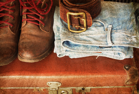 Pair of jeans, shoes, belt on a vintage suitcaseの写真素材