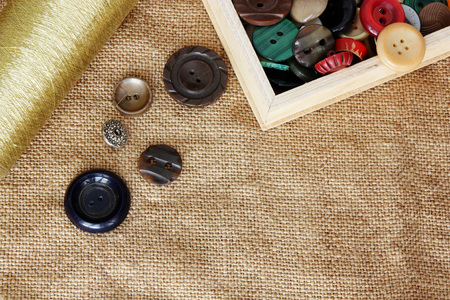 buttons and spool of thread on burlap backgroundの写真素材
