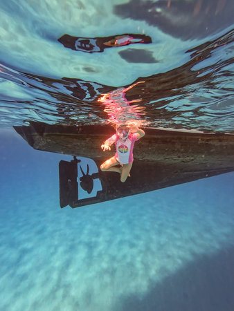 Small Girl Snorkels Under a Boat