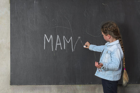 Girl Writes Mama on Chalkboard Learning.の写真素材