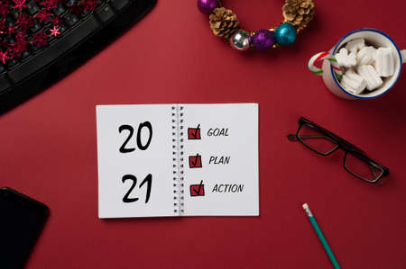 Workplace with a spiral notepad, mug with marshmallows and a keyboard, with New Year's decorations....