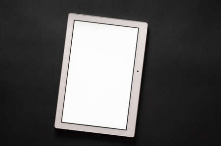 White tablet isolated on black background. Vertical screen with blank white space for typing.の写真素材