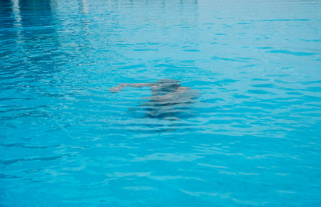 A man swimming in a swimming pool on a hot summer day.