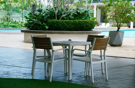 Table and chairs in the garden with a swimming pool in the backgroundの写真素材
