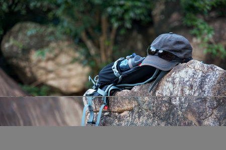 a tourist backpack with a cap and a drinking bottle lies on a large stoneの写真素材