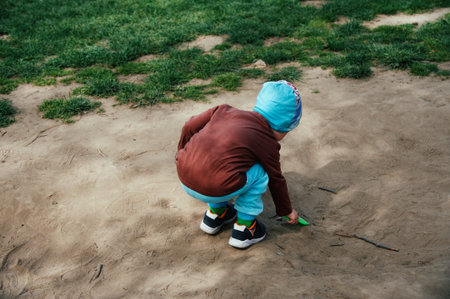 Little boy playing on the sand in the park. Outdoor activities for children.