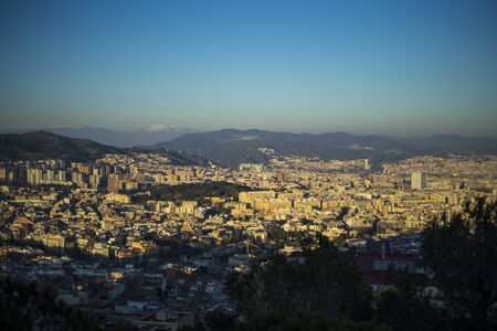 The view of the city of Barcelona from the hill in the suburb area during evening before sunset with clear sky and patchy cloudsの写真素材
