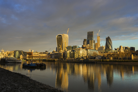 The view of the skyscrapers of City of London with its reflection on the Thames River in London, United Kingdom during a cloudy morning.の写真素材
