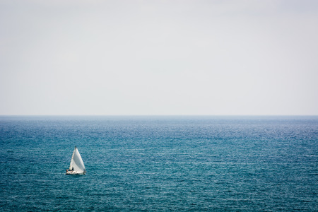 A sailboat sailing by sea on a foggy dayのeditorial素材