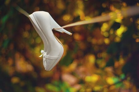white wedding shoes hanging on a ropeの写真素材