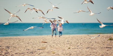 two people chasing seagulsの写真素材
